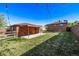A spacious backyard with lush lawn, detached garage, covered patio, and fencing at 2291 W 54Th Ave, Denver, CO 80221