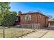 A brick home with mature tree, fenced yard, and driveway leading to the garage at 2291 W 54Th Ave, Denver, CO 80221