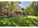 Expansive backyard with lush lawn, mature trees, brick accents, covered patio and second story deck at 8812 Blue Mountain Pl, Highlands Ranch, CO 80126