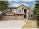 Charming two-story home boasts a three-car garage, brick accents, and lush landscaping under a beautiful sky at 8812 Blue Mountain Pl, Highlands Ranch, CO 80126