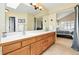 Bright bathroom with double sinks, wood cabinetry, and views into the main bedroom at 14194 W Amherst Ave, Lakewood, CO 80228