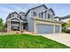 Charming two-story home with blue siding, brick accents, three-car garage and a well-manicured lawn at 14194 W Amherst Ave, Lakewood, CO 80228
