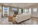 Sunlit living room with a comfortable white couch, large windows, and light wood flooring at 881 W 128Th Pl, Westminster, CO 80234