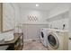A bright and modern laundry room with a front-load washer, dryer, decorative wallpaper and a utility sink at 17848 Gallup St, Broomfield, CO 80023