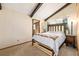 Cozy bedroom with exposed beams, wood-framed bed, soft lighting, and access to an ensuite bathroom at 97 Hedges Cir, Sedalia, CO 80135