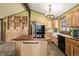 Inviting kitchen with natural wood cabinets, sleek black appliances, central island with stove, and modern sink at 97 Hedges Cir, Sedalia, CO 80135