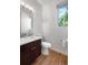 Modern half bathroom featuring a stylish vanity, a round toilet, and a window with a view of the outdoors at 4557 Stuart St, Denver, CO 80212