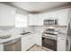 Modern kitchen featuring white cabinets, stainless steel appliances, and stone countertops at 3423 W Walsh Pl, Denver, CO 80219
