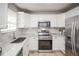 Well-appointed kitchen with white cabinets, stainless steel appliances, and bright lighting at 3423 W Walsh Pl, Denver, CO 80219