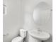 A simple half bathroom features a pedestal sink, toilet, and round mirror at 553 Homestead Ave, Brighton, CO 80601