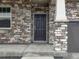 Close up of front door with stone details and a covered porch at 553 Homestead Ave, Brighton, CO 80601