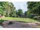 Manicured backyard with a spacious grassy area, mature trees, a fire pit and brick walk way at 11682 E Iowa Ave, Aurora, CO 80012