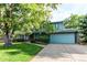 Charming two-story home featuring blue siding, mature trees, a landscaped yard, and an attached two-car garage at 11682 E Iowa Ave, Aurora, CO 80012