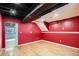 Unfinished basement with bright red walls and wood floors, offering renovation potential at 5587 S Simms Way, Littleton, CO 80127