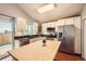 Bright kitchen features stainless steel appliances, light wood island and white cabinetry at 5587 S Simms Way, Littleton, CO 80127