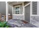 A welcoming front porch featuring stone accents, gray siding, and a modern door with stylish shutters at 28428 E 8Th Pl, Watkins, CO 80137