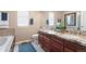 Bathroom with double sinks, granite countertops, dark wood cabinets, and separate tub at 9290 Melborne Ct, Parker, CO 80134