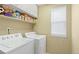 Functional laundry room with washer, dryer, storage shelves, and a bright window at 9290 Melborne Ct, Parker, CO 80134