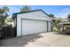 Detached white garage featuring a paved driveway and fenced yard with mature trees at 7891 Poplar St, Commerce City, CO 80022