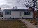 Quaint home featuring a well-lit exterior and inviting walkway, framed by decorative landscaping and a mature tree at 7891 Poplar St, Commerce City, CO 80022