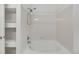 Bright white bathroom with a shower-tub combination and open shelving unit to the left at 5255 Memphis St # 317, Denver, CO 80239