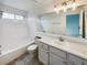 Bright bathroom featuring white cabinets, neutral countertops, a large mirror, and a tub-shower combo at 8536 S Upham Way, Littleton, CO 80128
