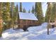 Charming cabin with snow-covered roof, wraparound deck, surrounded by beautiful evergreen trees at 324 County Road 672, Breckenridge, CO 80424