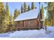 Charming cabin with snow-covered roof and wraparound deck, nestled among the beautiful evergreens at 324 County Road 672, Breckenridge, CO 80424