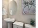 Bathroom features a pedestal sink, oval mirror, and decorative wall art at 6905 Fraser Cir, Frederick, CO 80530