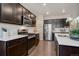 Modern kitchen with dark wood cabinetry, stainless steel appliances, and white countertops and backsplash at 6905 Fraser Cir, Frederick, CO 80530