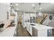 Well-lit kitchen with white cabinets, stainless steel appliances, island with sink, and a view of the staircase at 6520 Empire Ave, Frederick, CO 80516