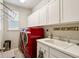 Laundry room showcasing red washer and dryer, white cabinets, and a utility sink at 6520 Empire Ave, Frederick, CO 80516