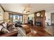 Comfortable living room featuring a fireplace, large window, ceiling fan, and hardwood floors at 8210 W 72Nd Pl, Arvada, CO 80005