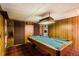 Finished basement with wood paneling features a pool table, carpeted floor, and suspended ceiling at 10247 W Arkansas Ave, Lakewood, CO 80232
