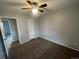 Bedroom featuring tan carpet, ceiling fan and a view into a hallway through a white door frame at 2617 S Cimarron St, Aurora, CO 80014