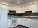 Kitchen featuring white cabinetry, stainless steel microwave and a view into the dining area at 2617 S Cimarron St, Aurora, CO 80014