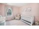 Bedroom with a white crib, glider chair, and light pink walls at 7415 E 158Th Pl, Thornton, CO 80602