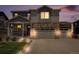 Charming two-story home features a stone facade, three-car garage, and a welcoming front porch at twilight at 7415 E 158Th Pl, Thornton, CO 80602