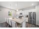 Bright kitchen featuring stainless steel appliances, a central island with seating, and white cabinetry at 7415 E 158Th Pl, Thornton, CO 80602