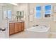 Bright bathroom featuring a shower, tub, double windows and a wooden vanity with neutral countertop at 10003 Atlanta St, Parker, CO 80134