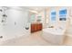 Bright bathroom featuring a shower, tub, double windows and a wooden vanity with neutral countertop at 10003 Atlanta St, Parker, CO 80134