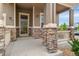 Inviting front porch with stone columns and a security screen door at 10003 Atlanta St, Parker, CO 80134