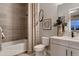 Bathroom with a shower-tub, beige tiled walls, and a decorative mirror above the toilet at 14111 Blue Stem St, Broomfield, CO 80020