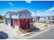 Rear view of a two-story home with a red and gray exterior and a garage entrance at 13616 E 103Rd Pl, Commerce City, CO 80022