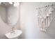 Simple powder room featuring modern fixtures, a white vessel sink, and decorative macrame wall art at 13616 E 103Rd Pl, Commerce City, CO 80022