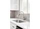 Close-up of kitchen sink with stainless steel faucet and herringbone tile backsplash at 1561 W Beekman Pl, Denver, CO 80221