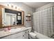 Well-lit bathroom with a vanity, granite countertop, a decorative mirror and a shower with striped curtain at 15274 W 64Th Ln # 206, Arvada, CO 80007
