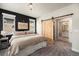 Comfortable bedroom with a wood accent wall and a rustic sliding barn door leading to the bathroom at 15274 W 64Th Ln # 206, Arvada, CO 80007
