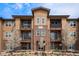 Exterior view of the apartment building with multiple balconies and spring trees in front at 15274 W 64Th Ln # 206, Arvada, CO 80007
