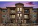 Stylish condo building showcasing brick accents, private balconies, and blossoming trees against a vibrant sunset sky at 15274 W 64Th Ln # 206, Arvada, CO 80007